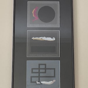 May include: Framed artwork featuring three panels with abstract designs. The top panel has a black circle with a pink and yellow figure. The middle panel shows a figure lying down. The bottom panel has a geometric design and a figure.