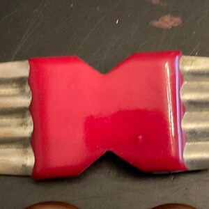 May include: A red and silver vintage brooch in the shape of a bow tie.