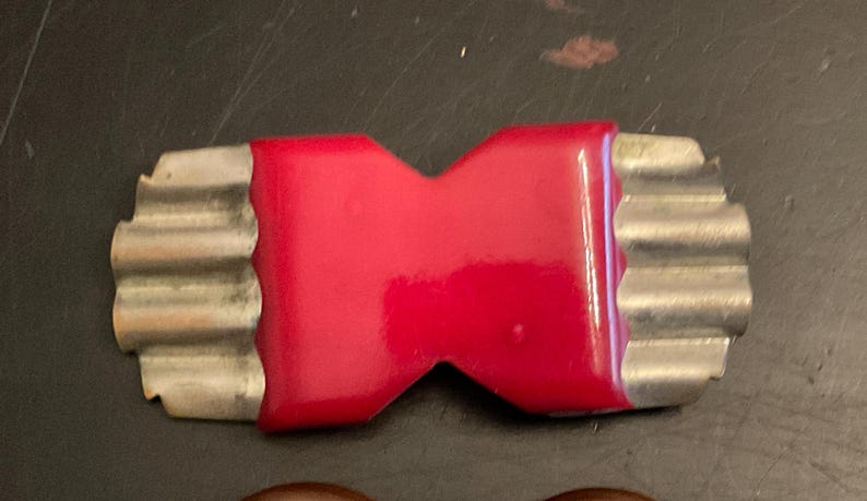 May include: A red and silver vintage brooch in the shape of a bow tie.