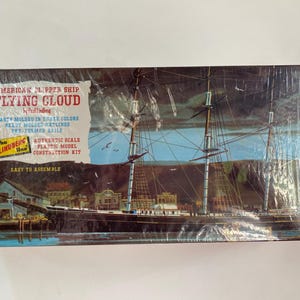 May include: A vintage model kit box for the American clipper ship "Flying Cloud." The box features a detailed illustration of the ship at sea, with text that reads "Easy to Assemble." The kit includes pre-formed rails and parts molded in true colors.