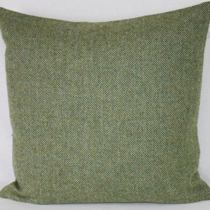May include: Green and beige herringbone patterned throw pillow. The pillow is made of a soft, textured fabric.