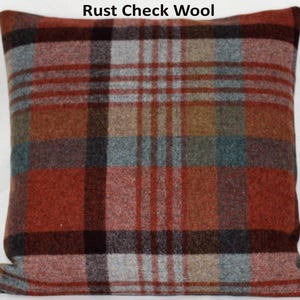 Può includere: Cuscino quadrato con motivo a quadri color ruggine. Il cuscino presenta un mix di tonalità rosse, marroni, grigie e verde acqua, creando un'estetica calda. Il testo "Rust Check Wool" è visibile nella parte superiore dell'immagine. Questo cuscino decorativo è adatto per l'arredamento della casa.