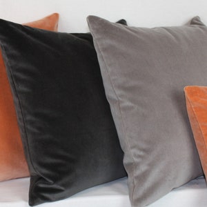 May include: Four decorative throw pillows in various colors. Two are a burnt orange color, one is a dark gray, and one is a light gray.