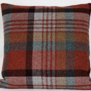 Puede incluir: Una almohada de tiro de cuadros rojos, marrones, grises y azules con una tela suave y texturizada.