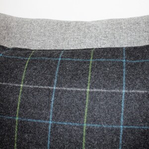 May include: Two decorative pillows. The front pillow is dark gray with a plaid pattern in blue, green, and white. The back pillow is a solid light gray.
