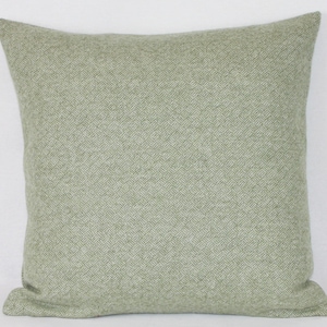 May include: A green and white herringbone patterned throw pillow. The pillow is made of a soft, textured fabric.