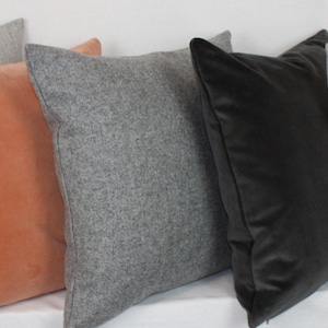 May include: Assortment of decorative throw pillows in various colors and textures.  The pillows include gray, orange, and black velvet.