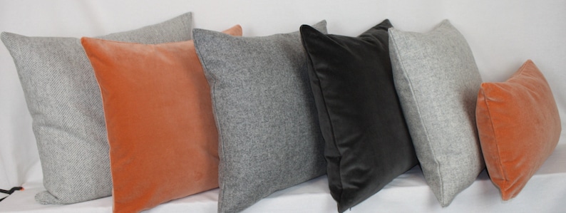 May include: Assortment of decorative throw pillows in various colors and textures.  The pillows include gray, orange, and black velvet.