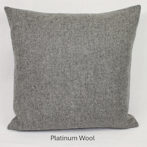 May include: A square, grey cushion made of platinum wool. The cushion has a soft, textured appearance and is a solid colour. The text "Platinum Wool" is at the bottom of the image.