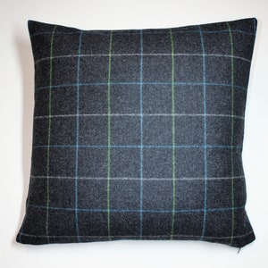 May include: Square decorative pillow with a dark gray plaid pattern. The plaid features a grid of blue, green, and white lines over the gray fabric. The pillow is square and has a soft, textured appearance.