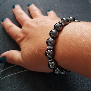 May include: A black beaded bracelet with small silver accents. The bracelet is made of round beads and has a shiny finish.