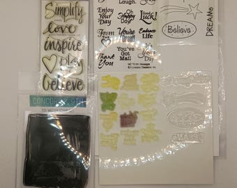 Peut inclure: Plusieurs tampons transparents avec des mots et des phrases inspirantes, dont "Simplifier", "Amour" et "Croire". Les ensembles présentent également des motifs de cœur et d'étoile, parfaits pour le scrapbooking.