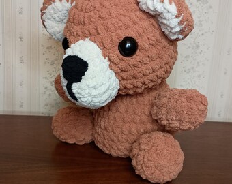 Peut inclure: Un ours en peluche fait à la main, de couleur marron chaud. L'ours a un museau et des oreilles intérieures blancs, des yeux noirs et un nez noir. L'ours est assis, avec ses bras et ses jambes visibles.
