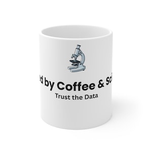 以下が含まれることがあります： 「Fueled by Coffee & Science」と「Trust the Data」の文字が入った白いセラミックマグカップ。薄い青とグレーの顕微鏡のグラフィックも特徴です。