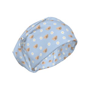 May include: A light blue beanie hat with a repeating pattern of small teddy bear faces and white daisy flowers. The hat is made of a soft fabric and is suitable for casual wear.