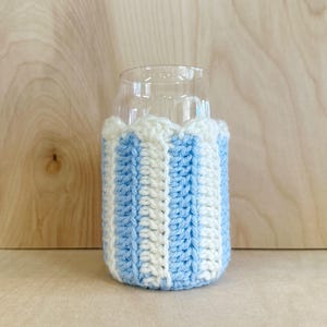 May include: A blue and white striped crocheted can cooler. The cooler is made of yarn and is designed to fit a standard-sized can.