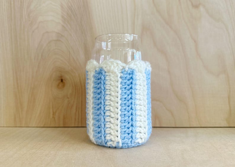 May include: A blue and white striped crocheted can cooler. The cooler is made of yarn and is designed to fit a standard-sized can.