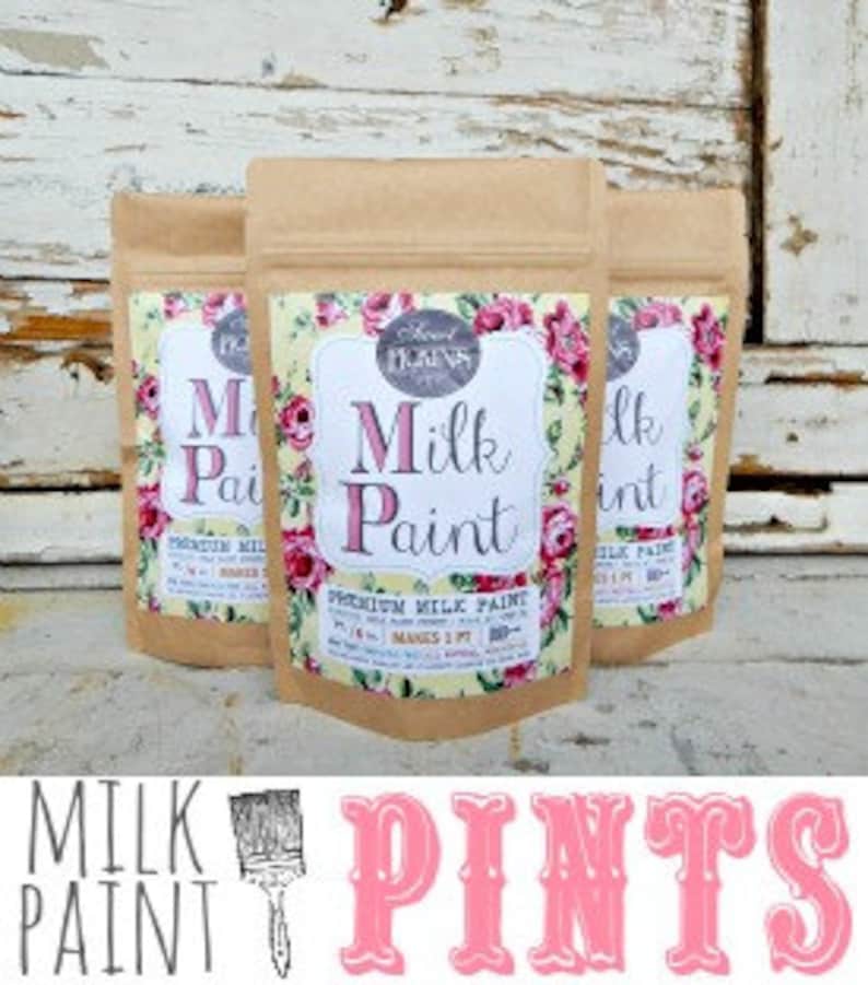 Pu&ograve; includere: Tre sacchetti di carta marrone con un'etichetta bianca su cui &egrave; scritto "Milk Paint" in lettere nere. L'etichetta ha un design floreale con rose rosa e gialle. I sacchetti sono impilati uno sopra l'altro.