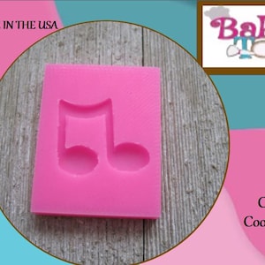 May include: A pink silicone mold in the shape of a musical note. The mold is food safe and made in the USA. Great for fondant, chocolates, clay, resin, crayons, marshmallow, and wax melts. The image also includes the text "Baker's Toybox".