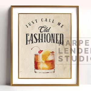 May include: Framed print with a gold border. The artwork features an Old Fashioned cocktail with a cherry and orange slice. Text reads "Just call me Old Fashioned". The background is a vintage paper texture.