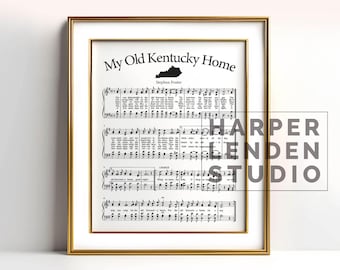 May include: A framed print of the sheet music for the song "My Old Kentucky Home" by Stephen Foster. The sheet music includes the lyrics and musical notation. The print is in black and white and has a gold frame.
