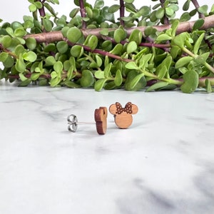 Peut inclure: Une paire de boucles d'oreilles en bois avec un motif de t&ecirc;te de Minnie Mouse &agrave; pois marrons et blancs et un n&oelig;ud marron.