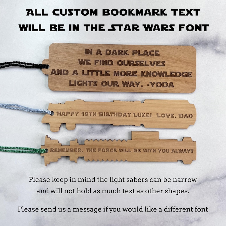 Op de afbeelding: Drie houten bladwijzers in de vorm van lichtzwaarden. De bovenste bladwijzer heeft de tekst "IN A DARK PLACE WE FIND OURSELVES AND A LITTLE MORE KNOWLEDGE LIGHTS OUR WAY. -YODA". De middelste bladwijzer heeft de tekst "HAPPY 19TH BIRTHDAY LUKE! LOVE, DAD". De onderste bladwijzer heeft de tekst "REMEMBER, THE FORCE WILL BE WITH YOU ALWAYS".