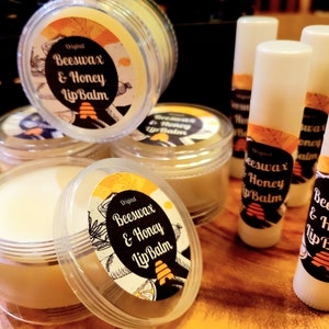 May include: A close-up of several lip balm containers. The containers are made of clear plastic and have a white lid. The lip balm is a light yellow color. The containers have a label with the text "Original Beeswax & Honey Lip Balm" and a beehive design.