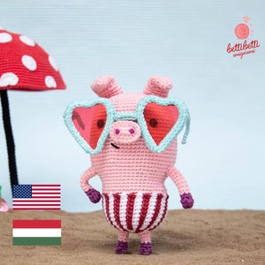 May include: A pink crocheted pig wearing heart-shaped sunglasses and a red and white striped swimsuit. The pig is standing on a sandy beach with a red and white mushroom umbrella in the background. The text "bettibetti amigurumi" is in the upper right corner of the image.
