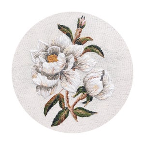 以下が含まれることがあります： ベージュの布地に白い刺繍の花が施されています。花は円形の枠の中にあります。