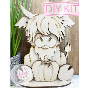 May include: DIY craft kit featuring a Highland cow holding a pumpkin. The kit includes all the pieces needed to assemble the wooden cutout. The kit is made by "DIY with Amber" and "The Makers Map".