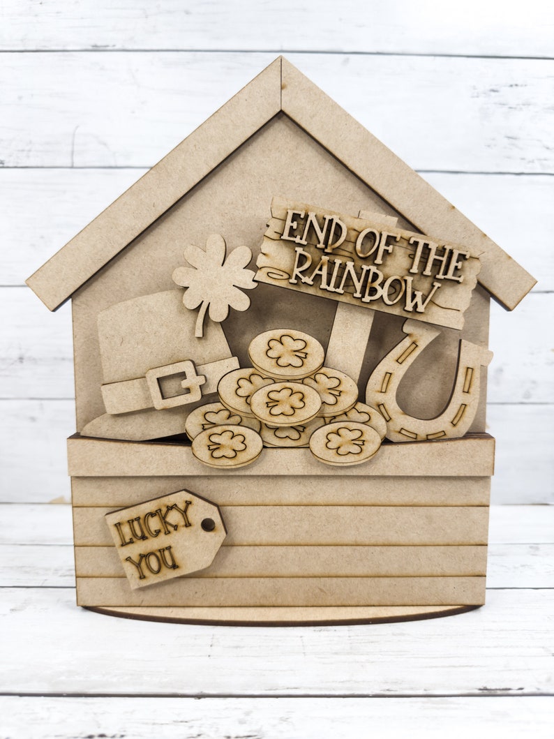 May include: Wooden craft project featuring a leprechaun's hat, a pot of gold coins, a horseshoe, and a shamrock. The sign reads "End of the Rainbow". The base of the project has a tag that reads "Lucky You".