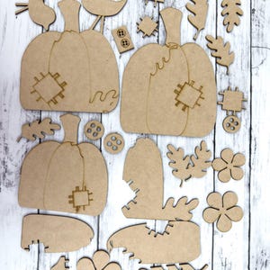 May include: A set of unfinished wooden craft cutouts featuring pumpkins, leaves, flowers, and buttons. The cutouts are perfect for fall-themed crafts and decorations.