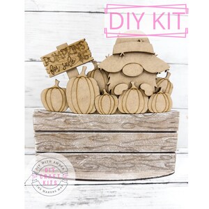 May include: A wooden DIY kit featuring a gnome surrounded by pumpkins. The gnome wears a hat and is positioned behind the pumpkins. A sign reads "Pumpkins for sale $5". The kit is set on a wooden crate, perfect for fall decor.