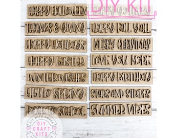 May include: A set of 10 wooden signs with various holiday and seasonal greetings. The signs are all the same size and shape, and they are made of a light brown wood. The text on the signs is in a white font. The signs are arranged in two rows of five. The signs read: Happy Halloween, Thanks & Giving, Happy Holidays, Happy Easter, Winter Wishes, Happy Fall Y'all, Merry Christmas, Love You More, Happy Birthday, Stars and Stripes, Back to School, Summer Vibes.
