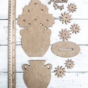 May include: Wooden craft kit for making a flower pot with flowers. The kit includes a vase, flowers, and a sign that says "Happy Mother's Day".