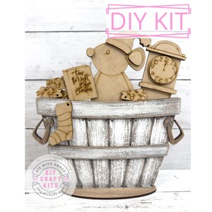 May include: A DIY craft kit featuring a wooden mouse wearing a hat, a clock, and a book titled "Twas the Night Before Christmas." The kit includes a wooden basket with a stocking and cheese. The text "DIY KIT" is at the top.