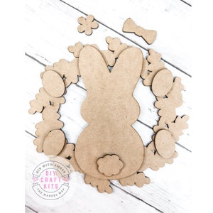 May include: A wooden craft kit featuring a bunny rabbit, eggs, and flowers. The pieces are unfinished and ready to be painted or decorated. DIY with Amber Craft Kits, The Makers Map.