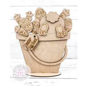 May include: A wooden craft kit featuring a bunny rabbit in a bucket with Easter eggs. The bucket has a tag that says "Easter Egg Hunt".