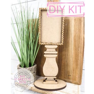 May include: DIY craft kit featuring a wooden frame with a beaded border, a pedestal base, and a round base. The kit is unfinished and ready to be painted or stained.