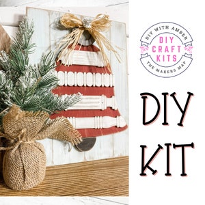 May include: DIY craft kit featuring a red and white wooden bell with a burlap bow. The kit is labeled "DIY Craft Kits The Makers Map DIY With Amber".
