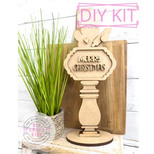 May include: Wooden DIY craft kit to make a Christmas sign with a snowman, a heart, and a sign that says "Merry Christmas".