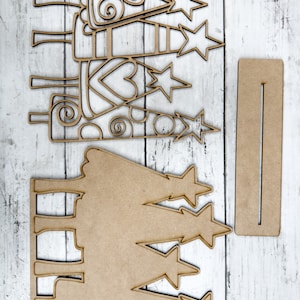 Op de afbeelding: Een set van drie onafgewerkte houten kerstboomversieringen met sterren en swirls. De versieringen zijn klaar om te worden geschilderd of versierd.