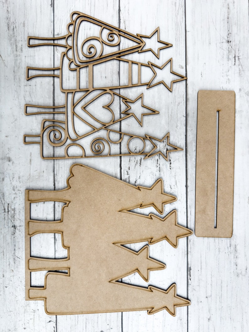 Op de afbeelding: Een set van drie onafgewerkte houten kerstboomversieringen met sterren en swirls. De versieringen zijn klaar om te worden geschilderd of versierd.