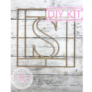 May include: A DIY kit featuring a wooden letter "S" within a square frame, designed for crafting. The kit includes the text "DIY KIT" in a pink rectangle. The logo "DIY with Amber" is visible in the lower left corner.