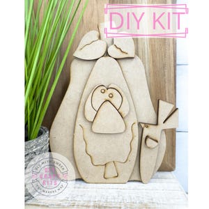 May include: DIY craft kit featuring a wooden cutout of a pear with a bird and leaves. The kit is unfinished and ready to be painted or stained.