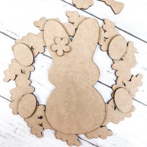 May include: A wooden craft kit for making an Easter bunny wreath. The kit includes a bunny shape, a wreath, eggs, flowers, and a bow.