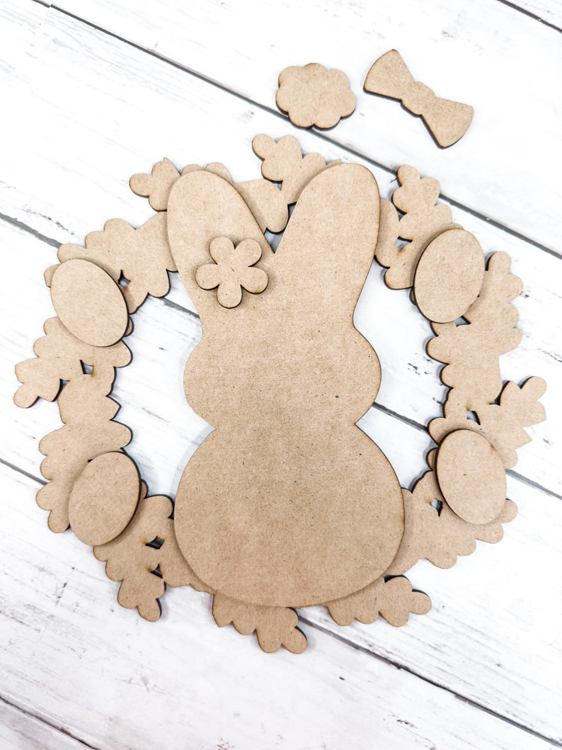 May include: A wooden craft kit for making an Easter bunny wreath. The kit includes a bunny shape, a wreath, eggs, flowers, and a bow.