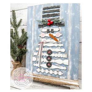 May include: A wooden snowman craft kit with a blue background. The snowman is made of wooden pieces, including a hat, scarf, and buttons. The kit includes a small wooden stand.