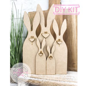 May include: DIY kit for making a family of five wooden bunny rabbits. The bunnies are different sizes and are made of unfinished wood.